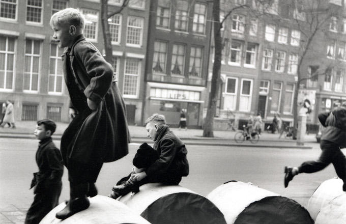Amsterdamse jongens spelen buiten op papierrollen die voor de krant bestemd zijn