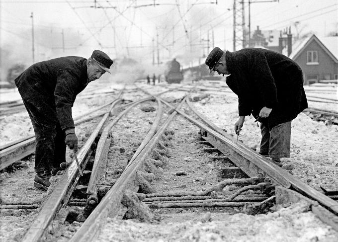 Een spoorwissel wordt onderhanden genomen door medewerkers van de Nederlandse Spoorwegen