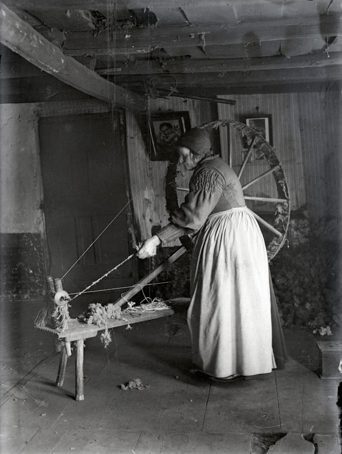 Op een middeleeuws spinnewiel draait deze thuisspinster haar draden van wol. Daar is wel wat handigheid voor nodig